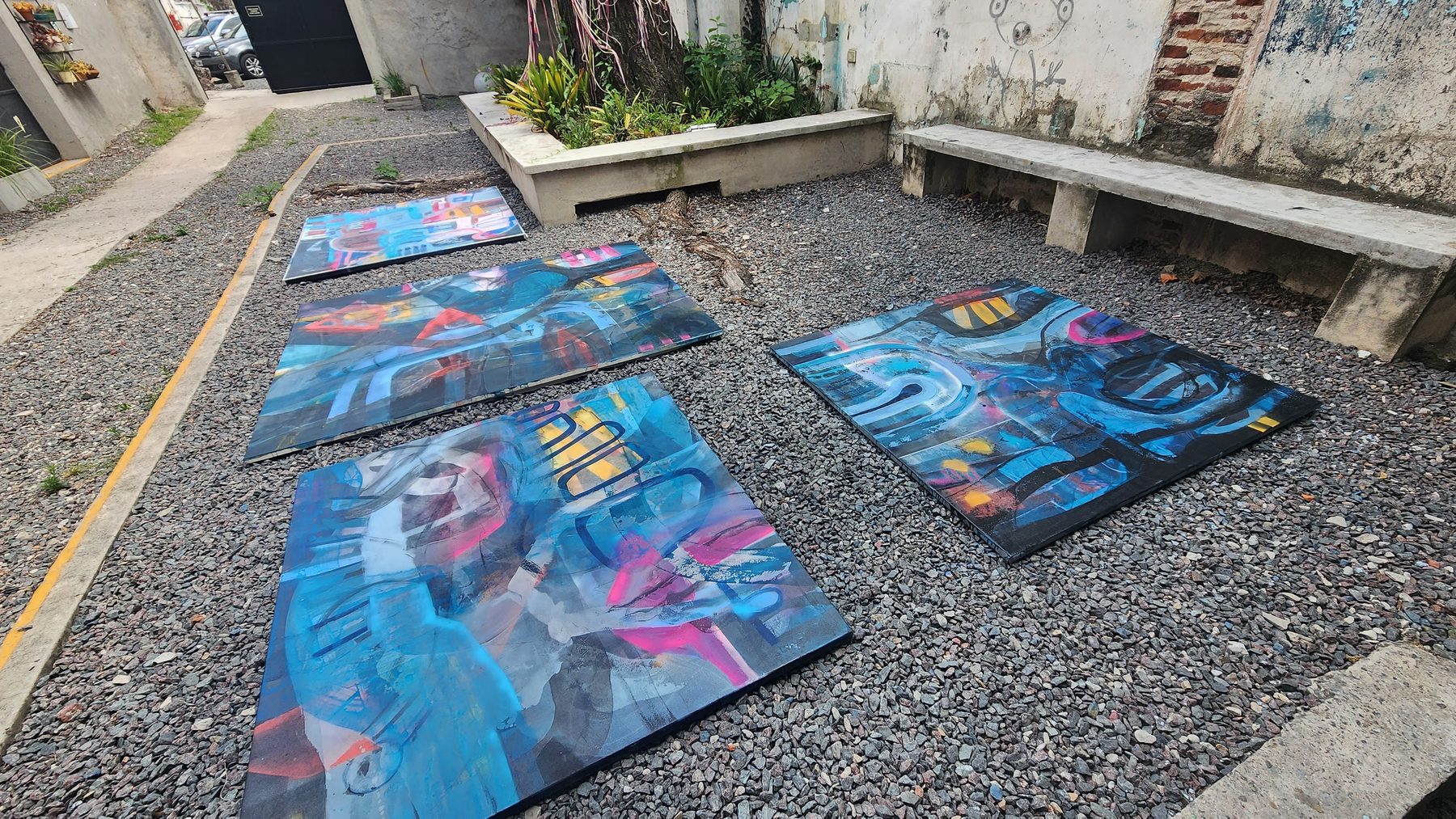 Pinturas apoyadas sobre la grava del patio, con luz natural